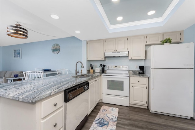 kitchen with a sink, a peninsula, white appliances, under cabinet range hood, and a raised ceiling