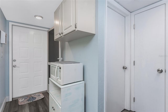 clothes washing area featuring baseboards and wood finished floors