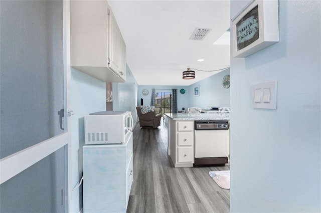 kitchen with white cabinetry, white appliances, visible vents, and wood finished floors