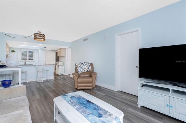 living area with baseboards, visible vents, and wood finished floors