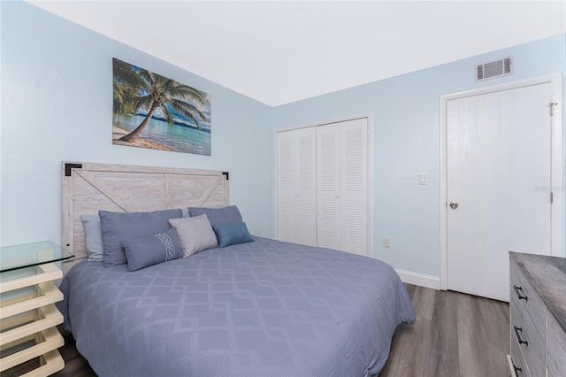 bedroom with baseboards, dark wood-style flooring, a closet, and visible vents