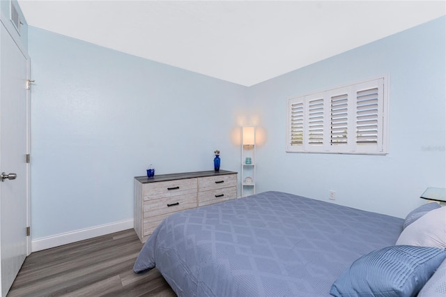 bedroom with baseboards, visible vents, and wood finished floors