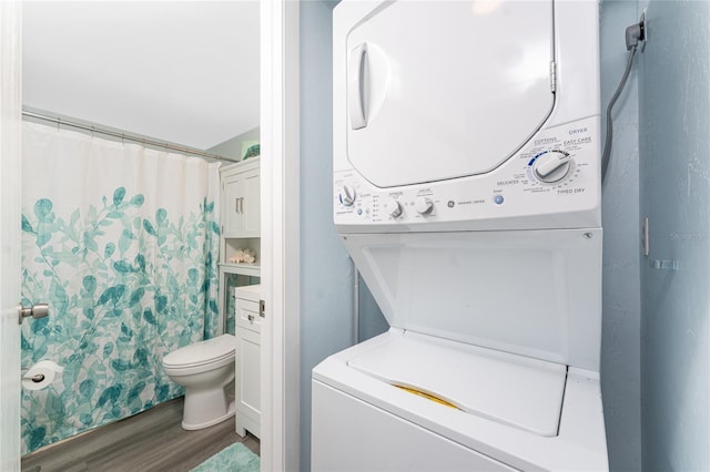 full bathroom with stacked washing maching and dryer, toilet, a shower with shower curtain, and wood finished floors
