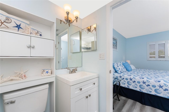 bathroom with connected bathroom, toilet, wood finished floors, a notable chandelier, and vanity