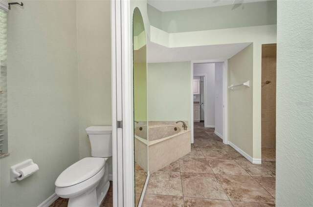12951 SW Kingsway Cir, Lake Suzy, FL 34269 - bathroom with toilet, a garden tub, tiled shower, and baseboards
