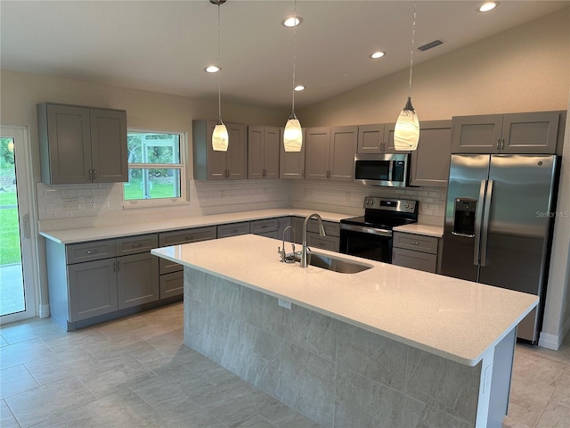 kitchen with a sink, gray cabinets, backsplash, light countertops, and appliances with stainless steel finishes