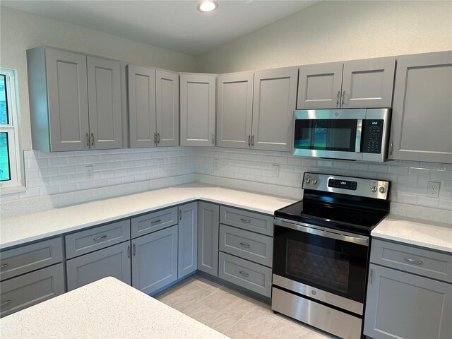kitchen with stainless steel appliances, gray cabinets, light countertops, decorative backsplash, and recessed lighting