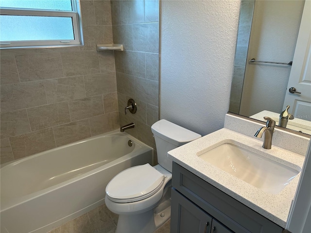 bathroom featuring toilet, vanity, shower / tub combination, and a textured wall