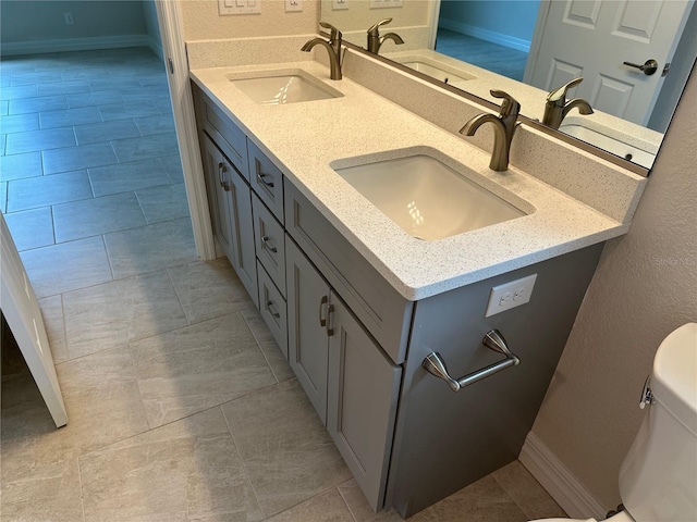 full bath with double vanity, toilet, and a sink