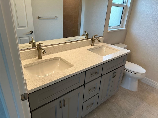 bathroom with toilet, double vanity, and a sink