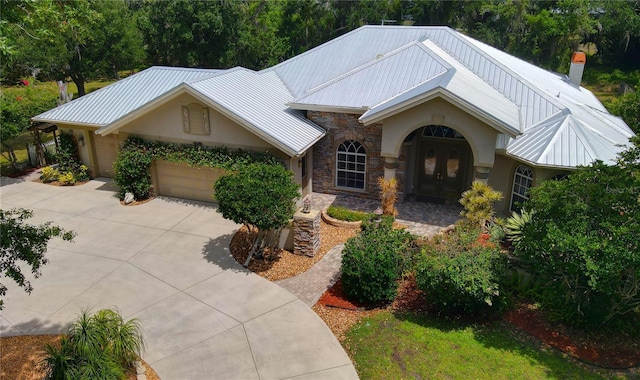 8596 SW Riverside Dr, Arcadia, FL 34269 - view of front of property featuring french doors, a garage, concrete driveway, metal roof, and stone siding