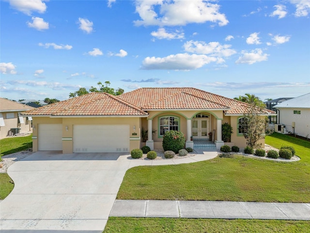 mediterranean / spanish house with an attached garage, a front lawn, stucco siding, and a tile roof