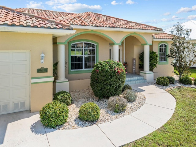 doorway to property with a tile roof, stucco siding, and a garage