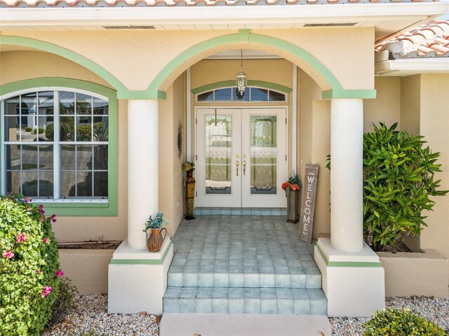 doorway to property with french doors, stucco siding, a tile roof, and a porch
