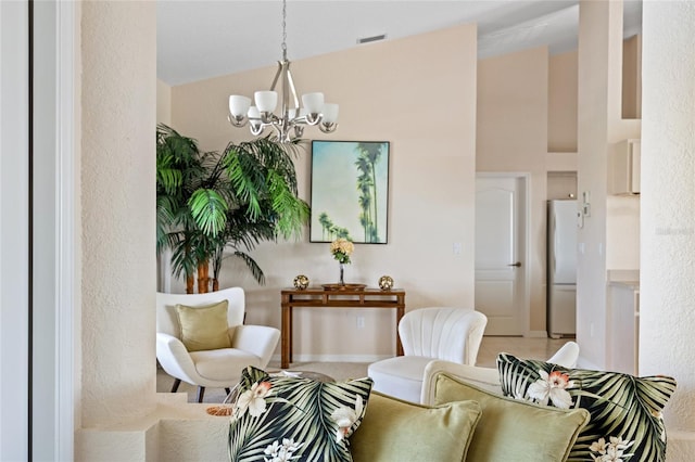 living area with a chandelier, baseboards, a textured wall, and high vaulted ceiling