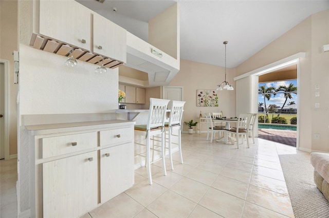 kitchen with light tile patterned floors, hanging light fixtures, high vaulted ceiling, and light countertops