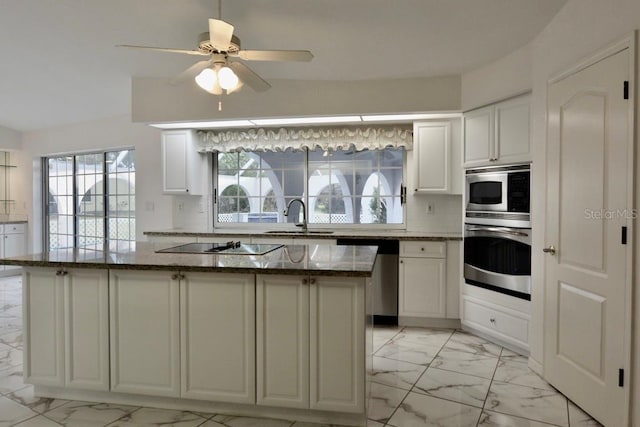 kitchen featuring stainless steel appliances, light marble finish floors, a sink, and white cabinets