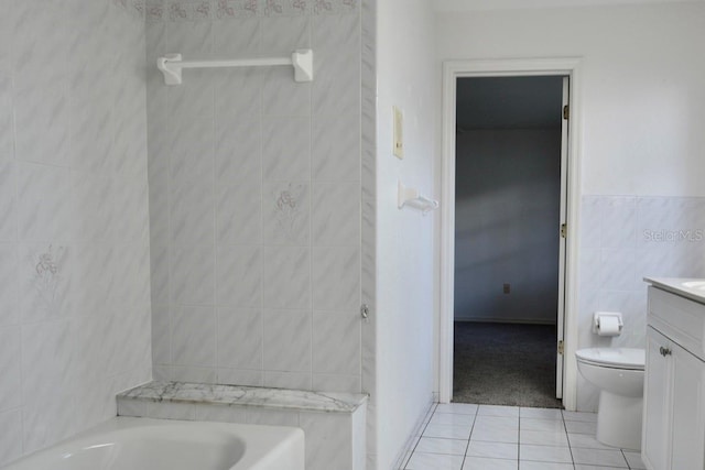 full bath featuring tile walls, tile patterned flooring, vanity, a bathtub, and toilet