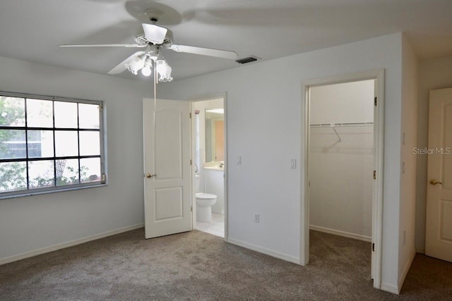 unfurnished bedroom with a walk in closet, carpet flooring, a closet, and ensuite bath