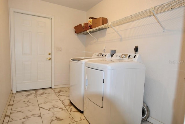 washroom featuring washer and clothes dryer, light marble finish floors, and baseboards