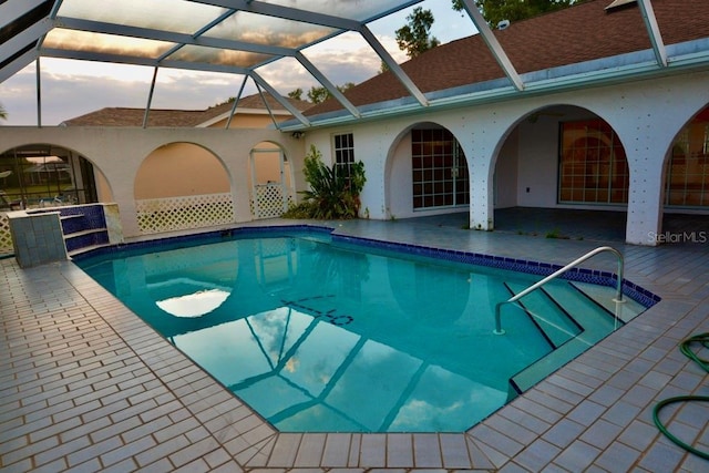 swimming pool with a patio and glass enclosure