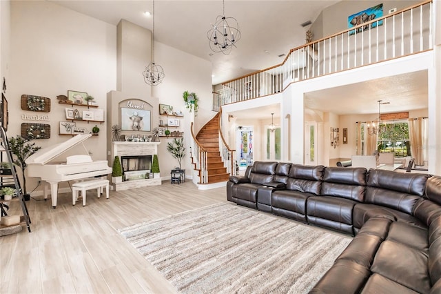 7192 SW Albritton St, Arcadia, FL 34266 - living room featuring a towering ceiling, a chandelier, a fireplace with raised hearth, wood finished floors, and stairway