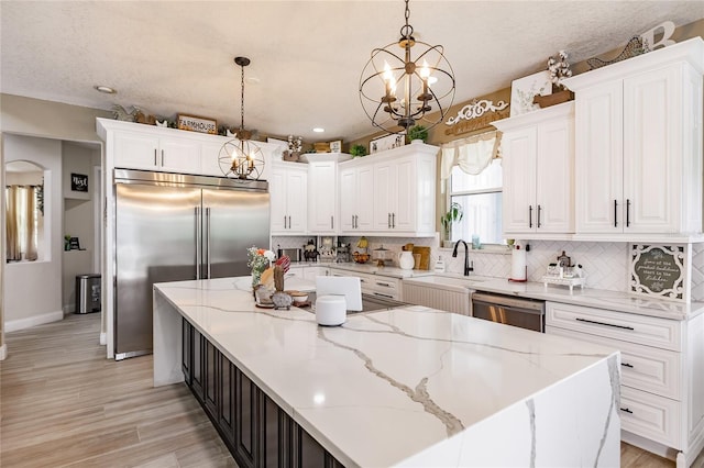 7192 SW Albritton St, Arcadia, FL 34266 - kitchen with appliances with stainless steel finishes, a chandelier, a kitchen island, white cabinets, and backsplash