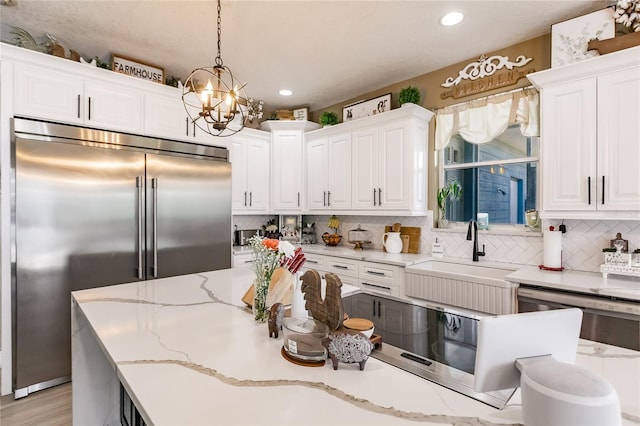 7192 SW Albritton St, Arcadia, FL 34266 - kitchen featuring appliances with stainless steel finishes, a sink, backsplash, white cabinets, and a chandelier