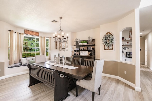 7192 SW Albritton St, Arcadia, FL 34266 - dining area with light wood finished floors, a chandelier, baseboards, and arched walkways