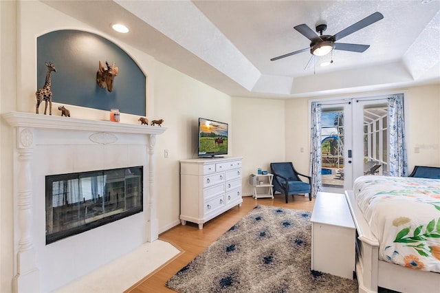 7192 SW Albritton St, Arcadia, FL 34266 - bedroom featuring access to exterior, light wood-style floors, a fireplace, recessed lighting, and a tray ceiling
