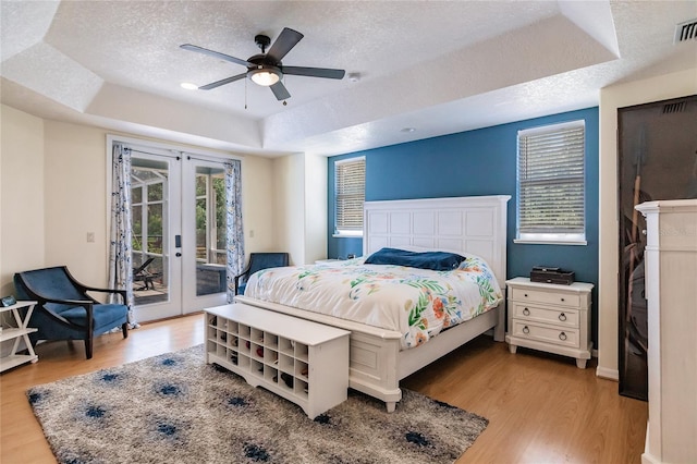 7192 SW Albritton St, Arcadia, FL 34266 - bedroom with a tray ceiling, french doors, access to exterior, light wood-type flooring, and a textured ceiling