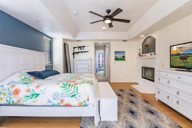 7192 SW Albritton St, Arcadia, FL 34266 - bedroom with a fireplace with flush hearth, light wood-type flooring, a raised ceiling, recessed lighting, and ceiling fan