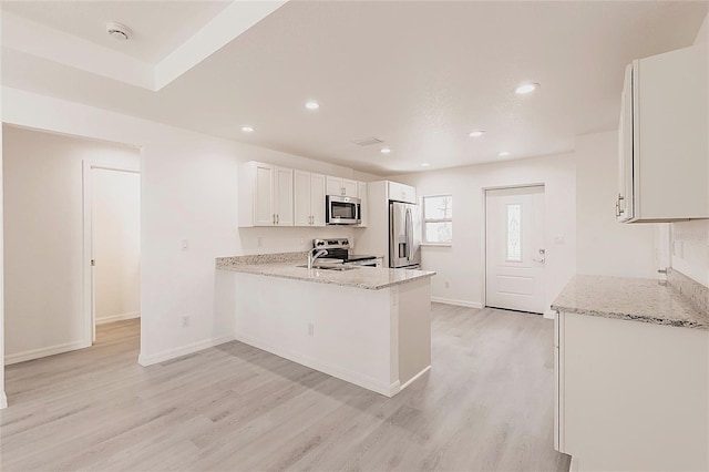 27438 Corinthian Dr, Punta Gorda, FL 33955 - kitchen with appliances with stainless steel finishes, light wood-style floors, a peninsula, white cabinets, and light stone counters