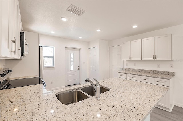 27438 Corinthian Dr, Punta Gorda, FL 33955 - kitchen featuring stainless steel appliances, a sink, white cabinetry, a peninsula, and light stone countertops
