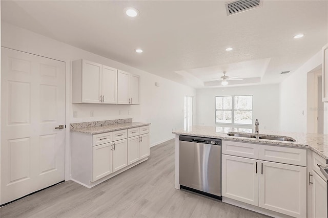 27438 Corinthian Dr, Punta Gorda, FL 33955 - kitchen with stainless steel dishwasher, a sink, light wood-style flooring, a raised ceiling, and ceiling fan