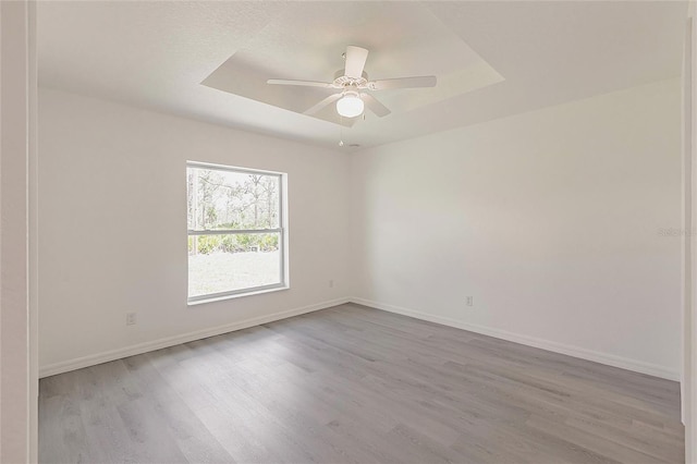 27438 Corinthian Dr, Punta Gorda, FL 33955 - empty room with a tray ceiling, wood finished floors, baseboards, and a ceiling fan