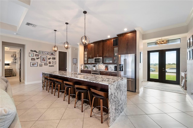 3527 NW 8th Ter, Cape Coral, FL 33993 - kitchen with appliances with stainless steel finishes, a chandelier, dark brown cabinets, a kitchen bar, and ornamental molding