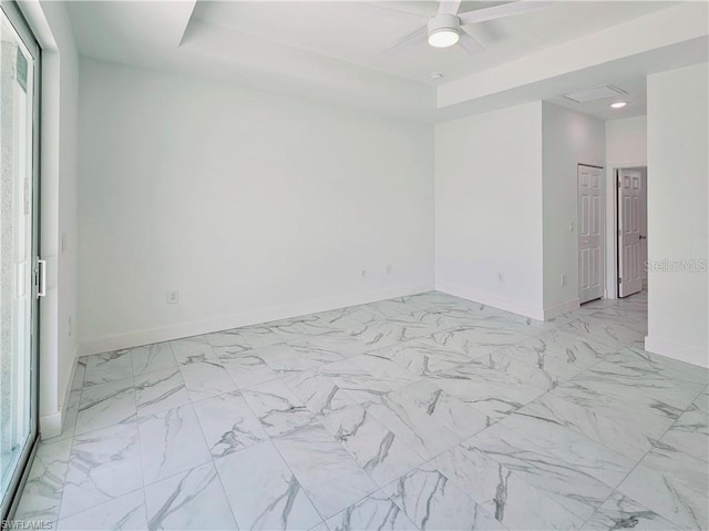 empty room featuring baseboards, ceiling fan, recessed lighting, a tray ceiling, and light marble finish floors