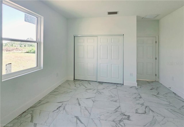 unfurnished bedroom with baseboards, light marble finish floors, and a closet