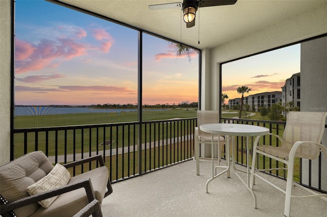 sunroom / solarium with ceiling fan and a water view
