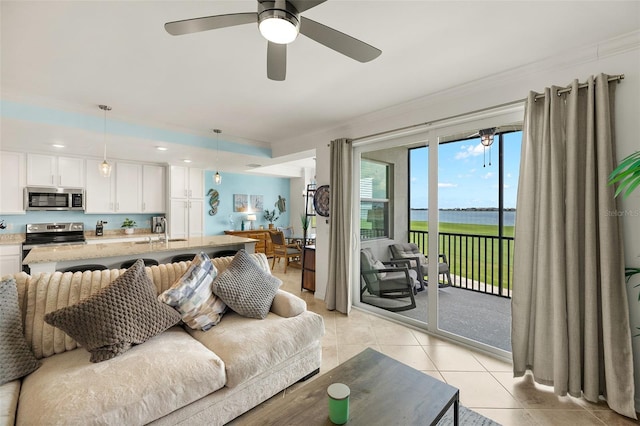 living area with ornamental molding, light tile patterned flooring, a water view, and a ceiling fan