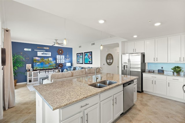 kitchen with appliances with stainless steel finishes, a sink, ornamental molding, open floor plan, and white cabinets