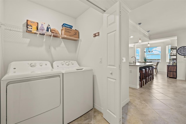 laundry room with washer and clothes dryer, baseboards, light tile patterned flooring, and crown molding