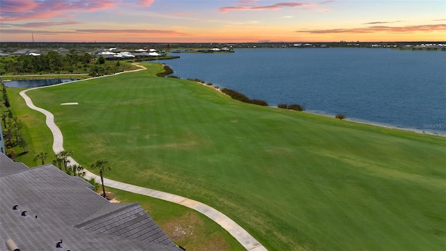 drone / aerial view of a nearby body of water and a golf course