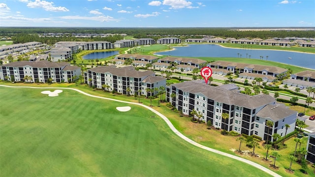 drone / aerial view of a large body of water, a golf course, and apartment complex / building