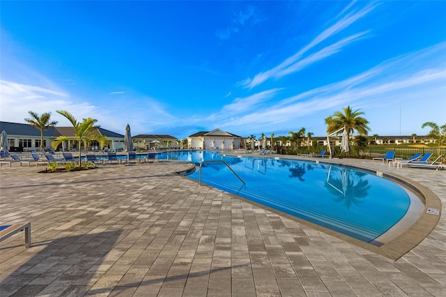 community pool featuring a patio, a residential view, and fence