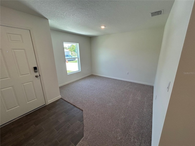 6 Whittier Ln, Palm Coast, FL 32164 - spare room with baseboards, dark wood-style floors, a textured ceiling, and dark carpet