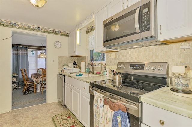 12018 Saragossa Ln, North Port, FL 34287 - kitchen featuring stainless steel appliances, a sink, white cabinets, and backsplash