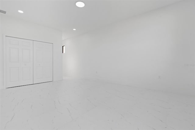 unfurnished bedroom featuring marble finish flooring, a closet, and recessed lighting