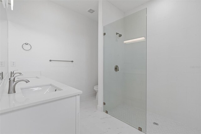 bathroom featuring a tile shower, marble look tiles, toilet, and double vanity